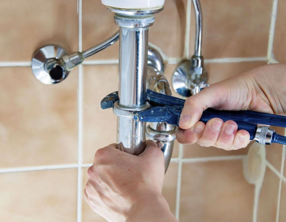 Plumber tightening a sink faucet supply line with a wrench