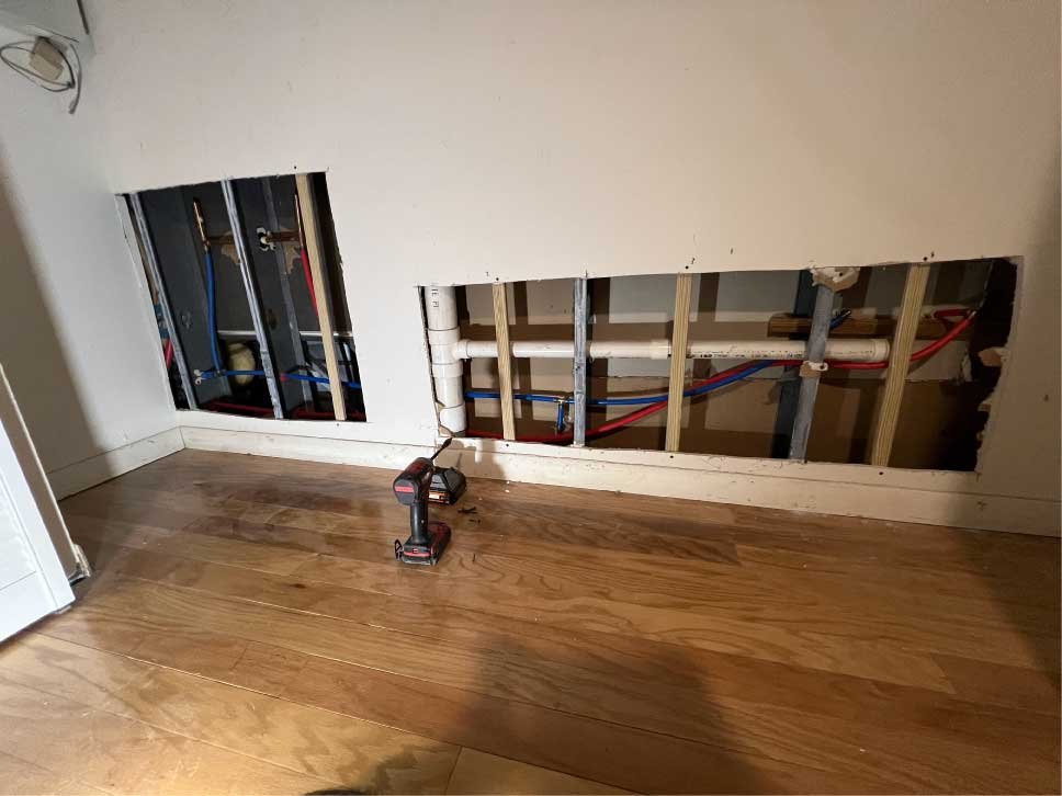 Open wall showing new water supply lines during a plumbing repair