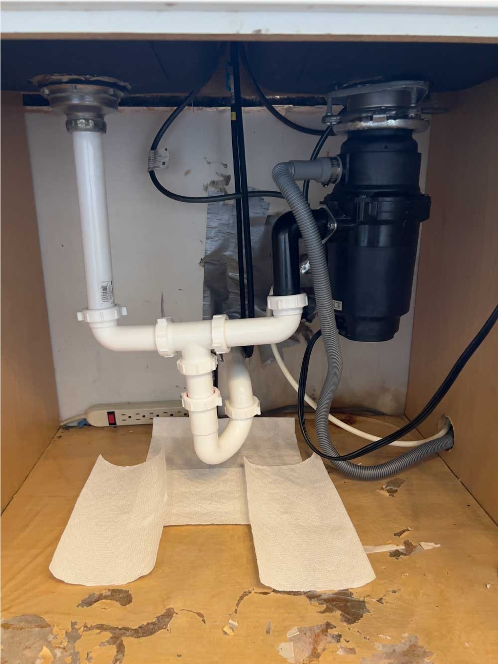 Garbage disposal and new drain plumbing installed under a kitchen sink