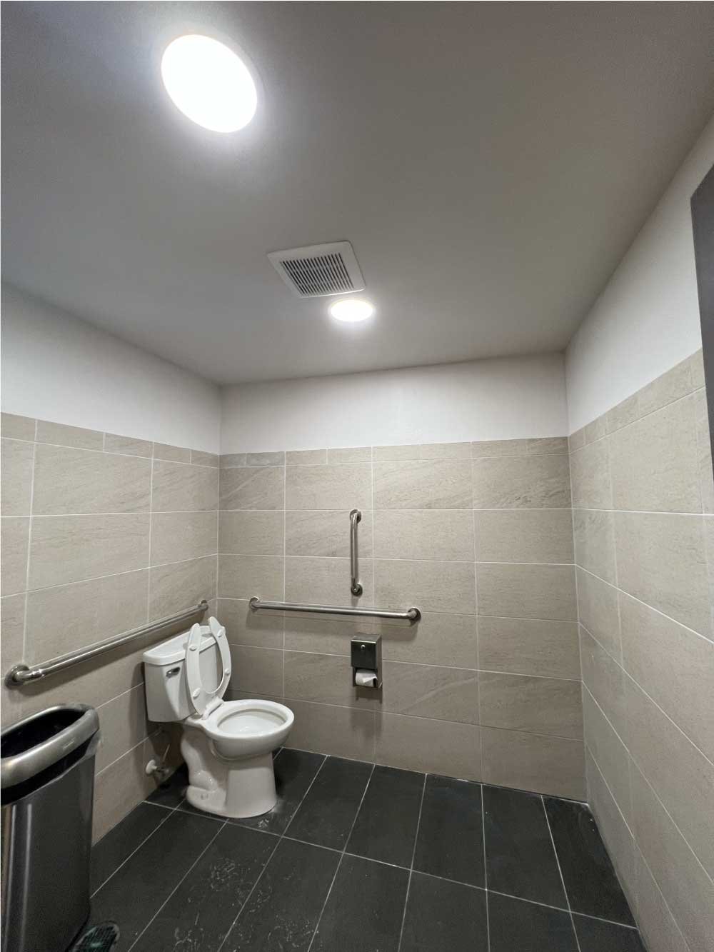 Accessible commercial restroom with new tile, grab bars and lighting