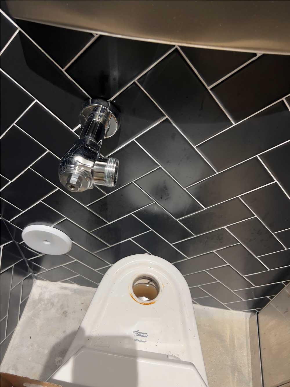 Black herringbone tile shower with a new shower valve and fixtures