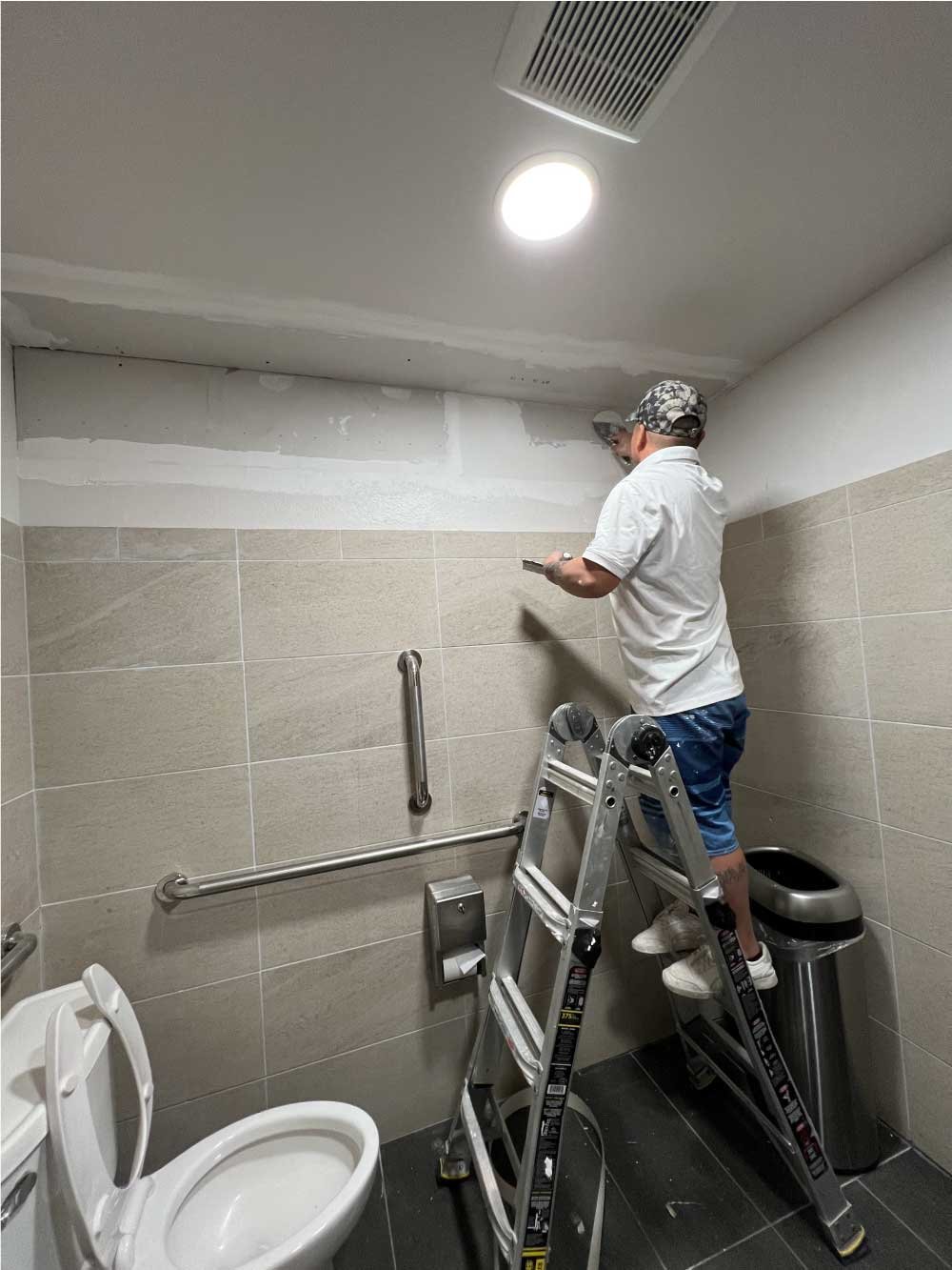 Handyman installing grab bars in an accessible commercial restroom