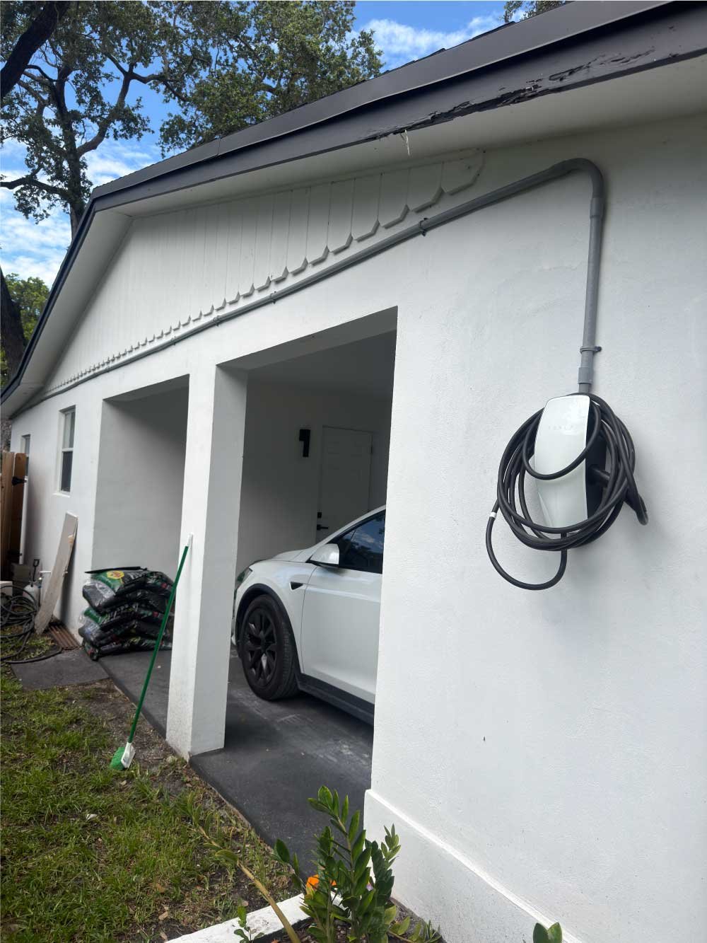 EV charger installed on a garage wall beside a parked electric car