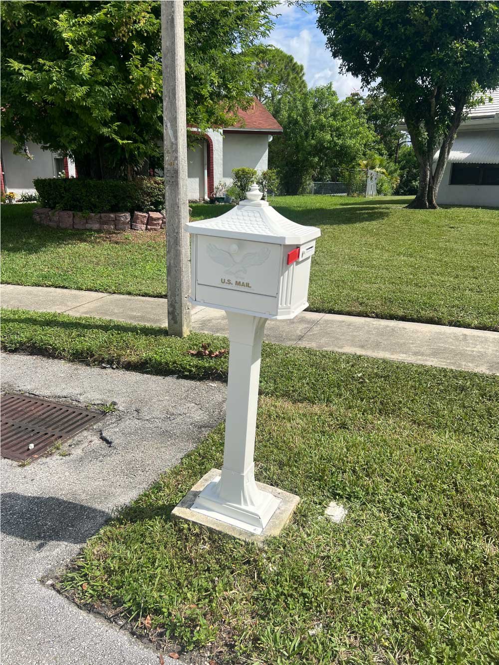 New white mailbox and post installed at the curb of a home