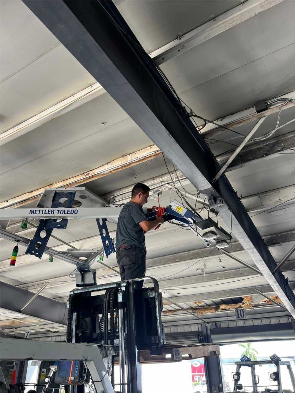 Technician on a lift installing overhead equipment in a commercial warehouse