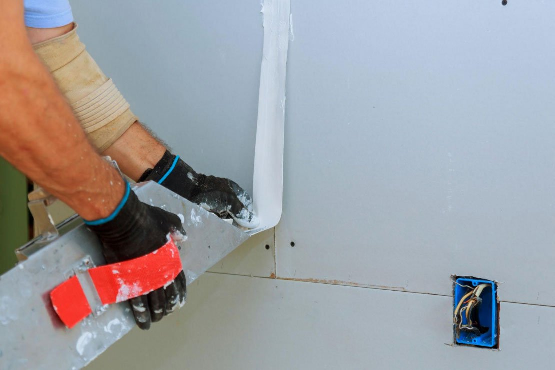 Drywall repair being finished with joint compound and a taping knife