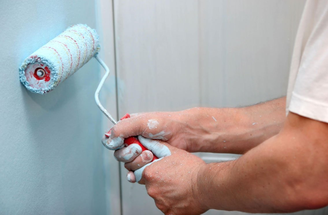 Painter applying fresh paint to an interior wall with a roller