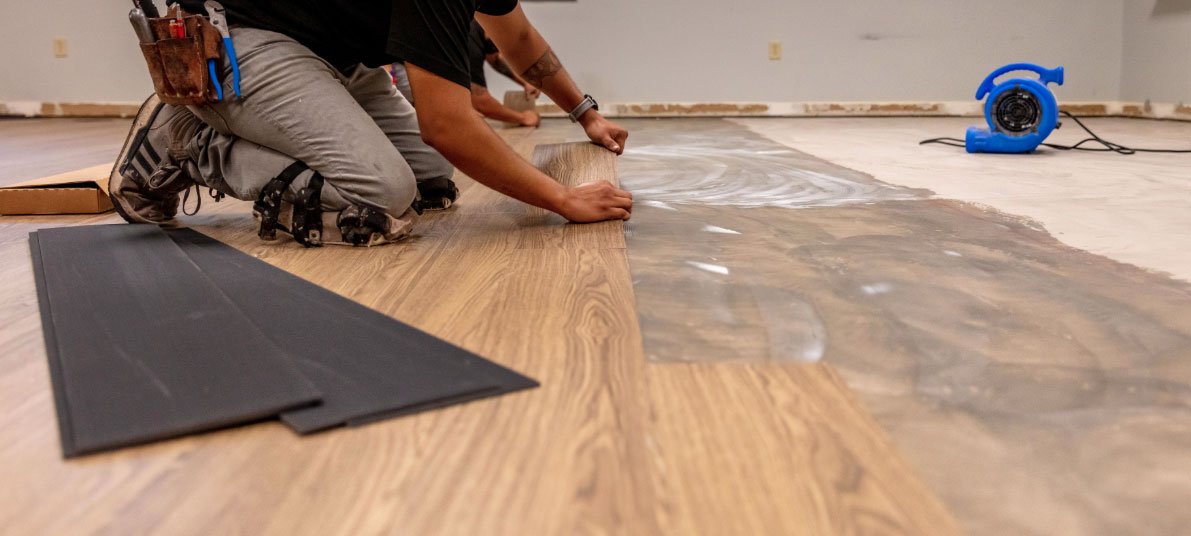 Handyman installing vinyl plank flooring in a living room