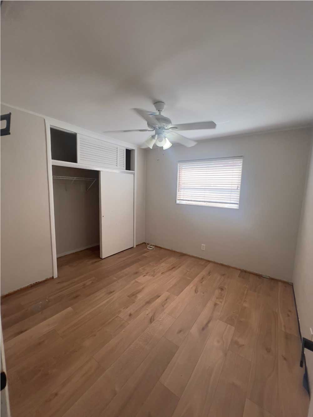 Empty bedroom with new flooring and a ceiling fan installed