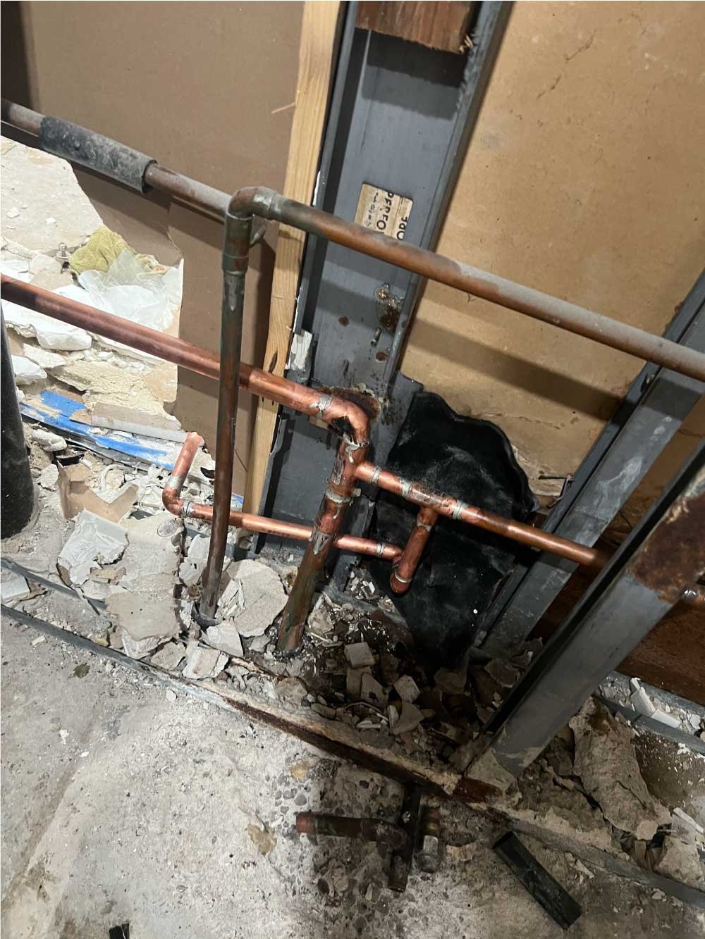 Copper pipe repiping inside an opened wall during a plumbing repair