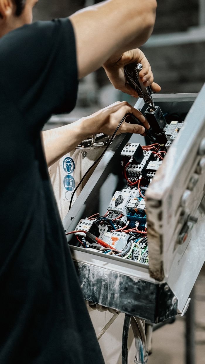 Technician adjusting wires in an electrical control panel for maintenance